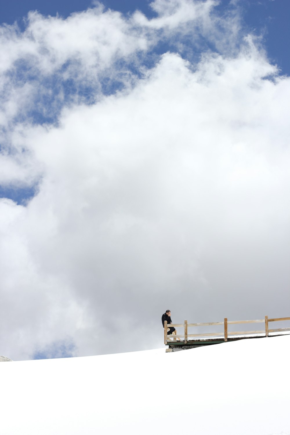 man in black shirt standing on white concrete wall under white clouds during daytime