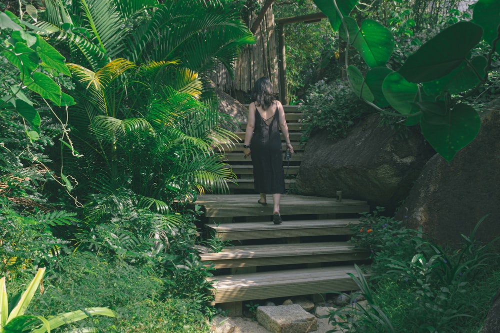 woman in black dress standing on wooden bridge