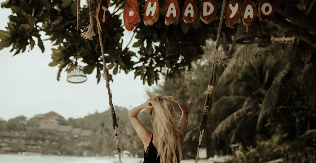 woman in black tank top hanging on brown wooden swing during daytime