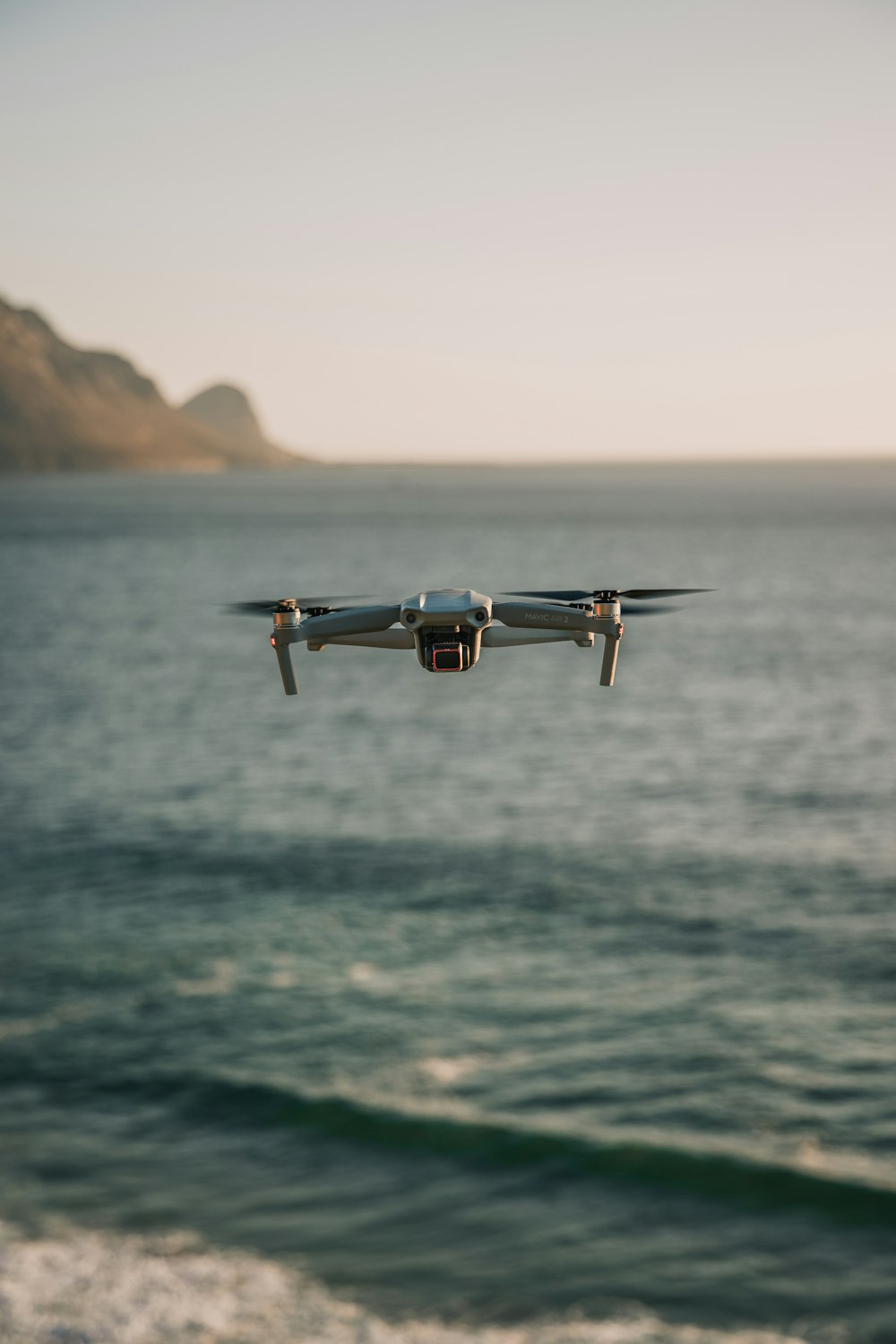 Drone blanc et noir volant au-dessus de la mer pendant la journée