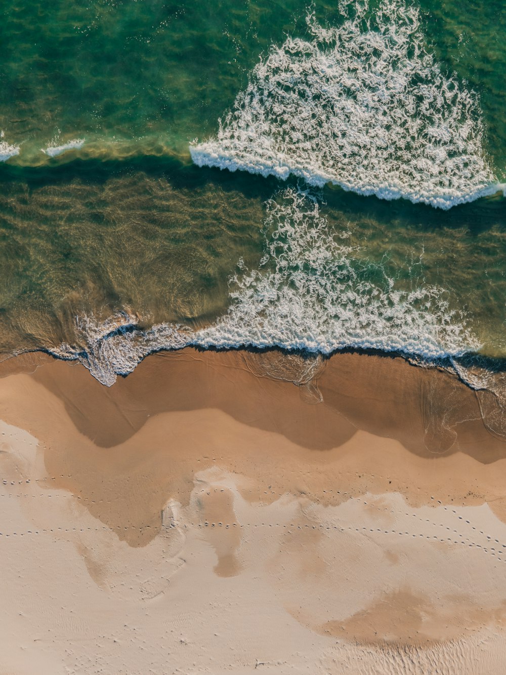 Vue aérienne des vagues de la mer s’écrasant sur le rivage pendant la journée