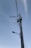 A tall utility pole is equipped with multiple wires and two large cylindrical transformers. A streetlamp extends outward from the pole, which is set against a clear blue sky.