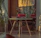 Cozy corner featuring a window hanging casting colorful light on a comfy chair beside books.