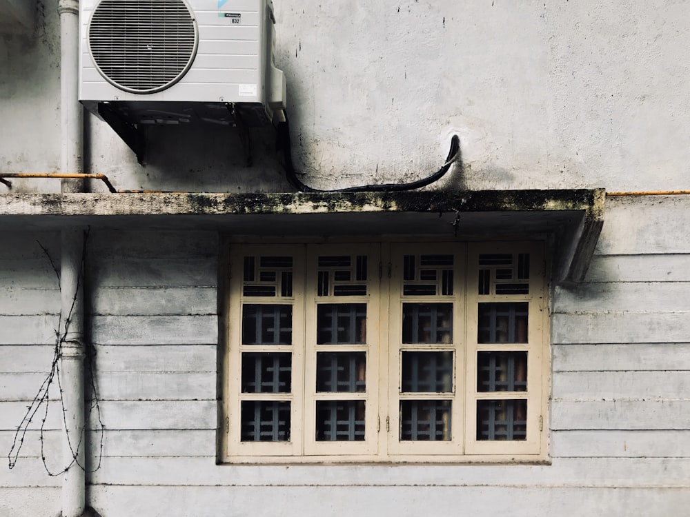 white window type air conditioner on white concrete wall