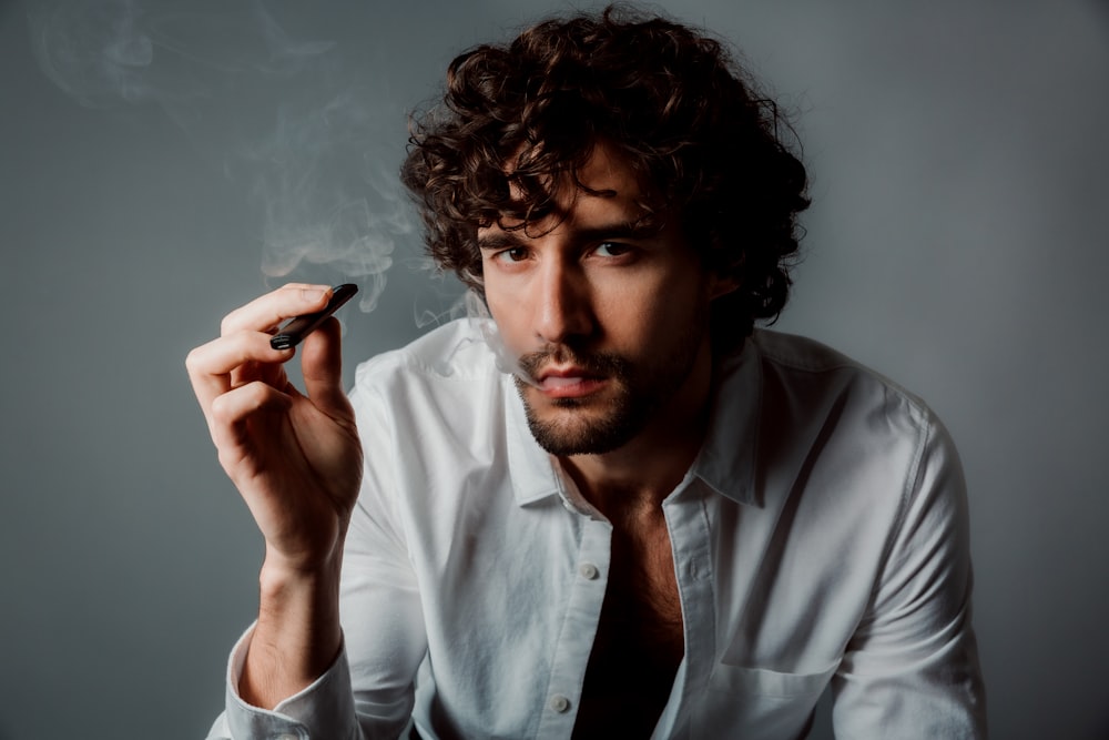 man in white button up shirt holding black smartphone