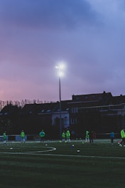 A vibrant football team lined up on the pitch wearing matching custom kits featuring bold green accents.