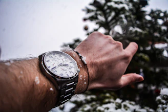 Close-up of a hand gently spinning a black obsidian mantra bracelet against a backdrop of soft white snow.