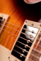 Close-up of an electric guitar, focusing on the strings and pickups with a warm, rich gradient on the body.