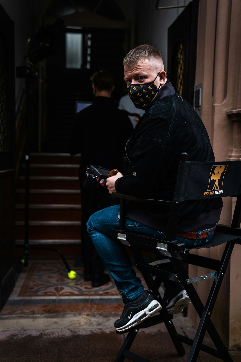 man in black jacket and blue denim jeans sitting on black metal bench
