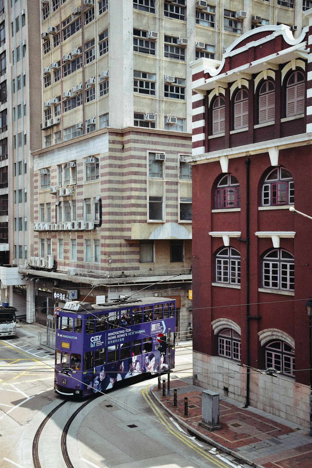 blue and red bus on road near brown concrete building during daytime