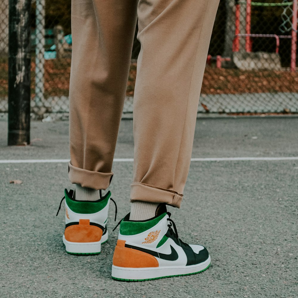 person in brown pants and green and white nike sneakers