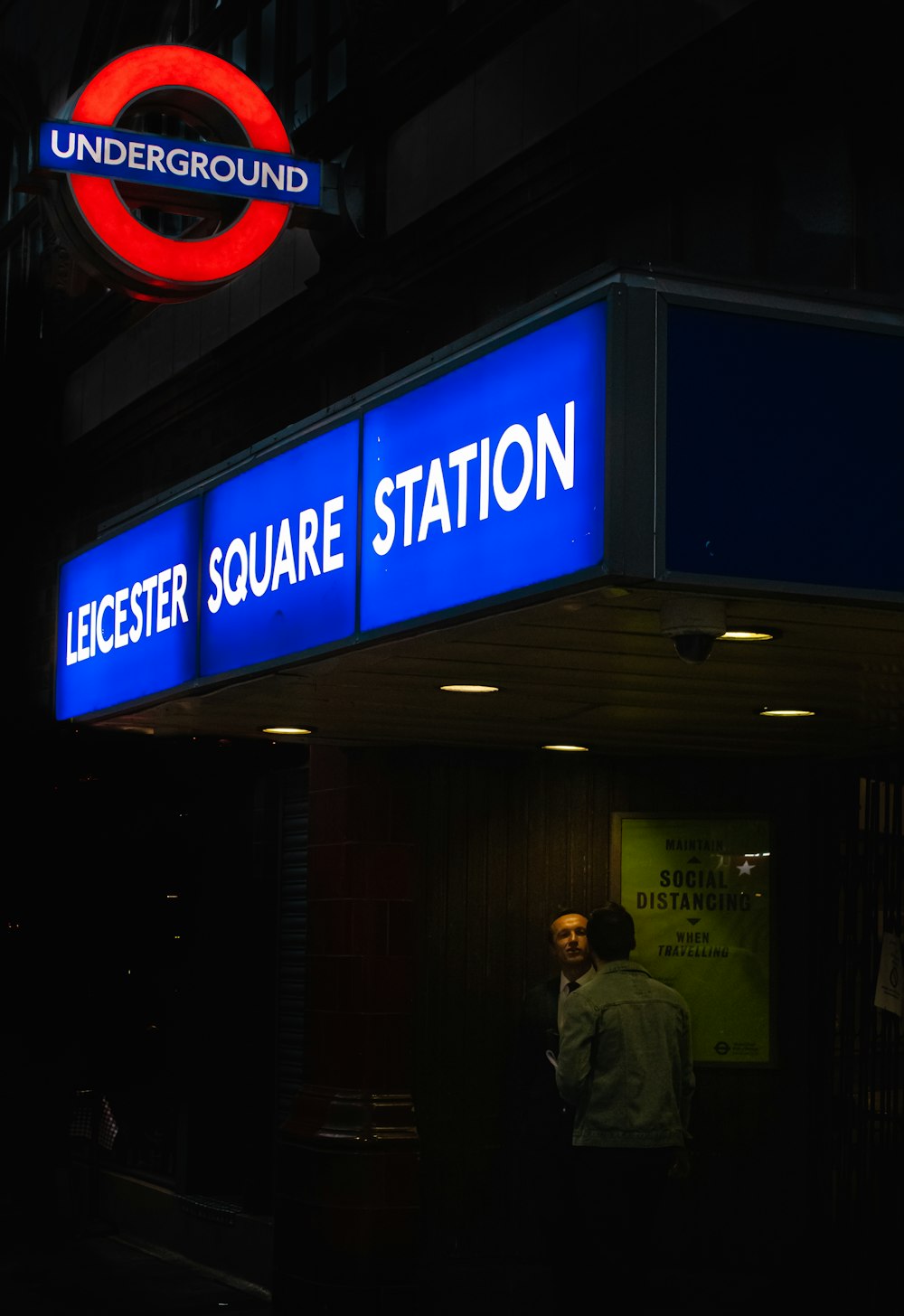a man standing in front of a sign for a subway station