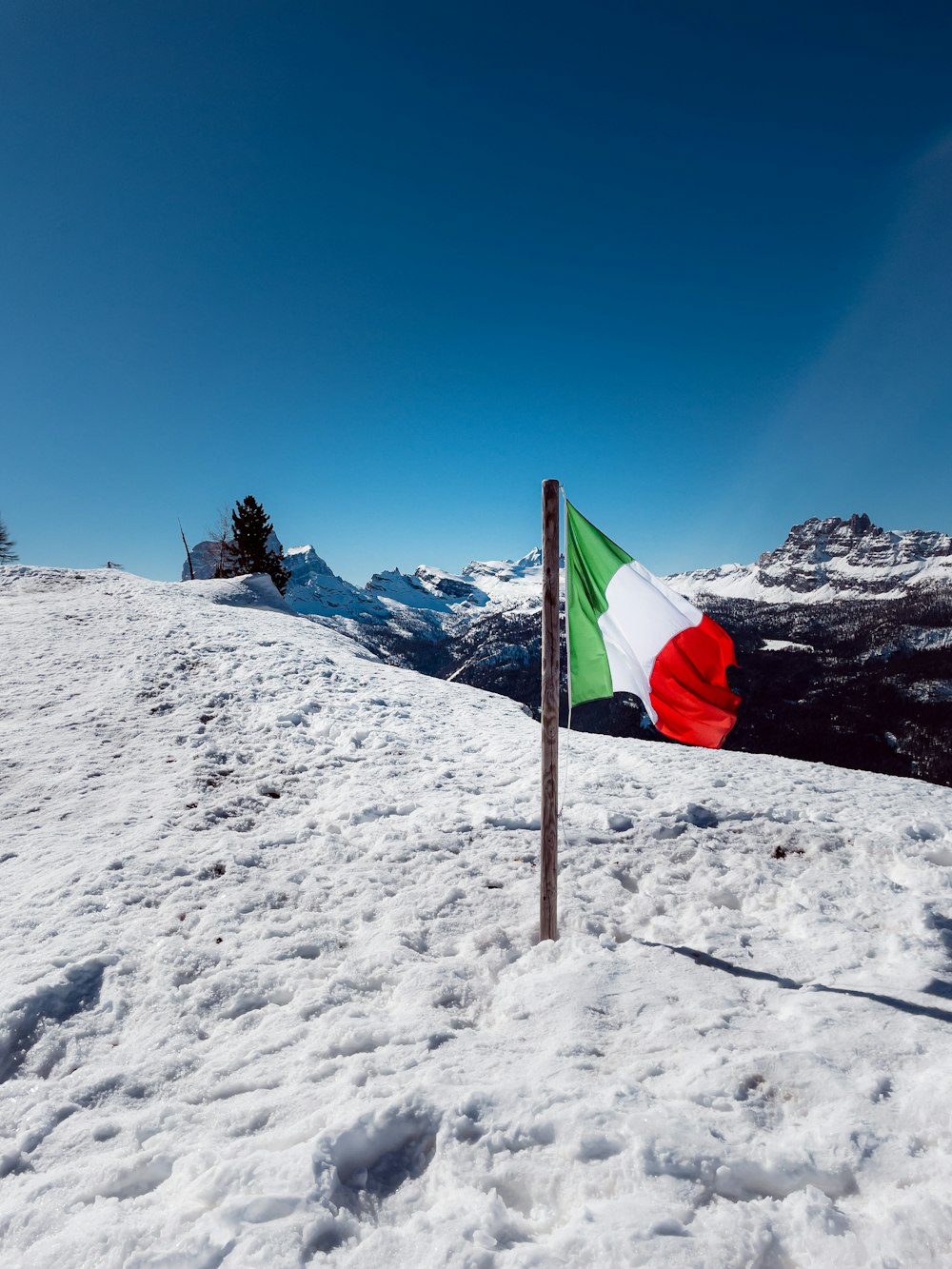 bandera roja, blanca y verde en la montaña cubierta de nieve bajo el cielo azul durante el día