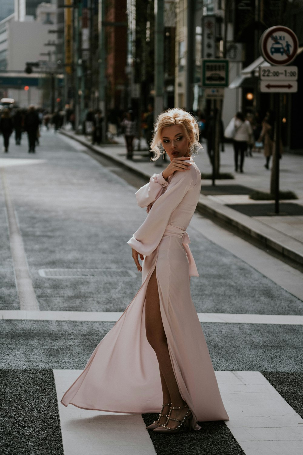 Femme en robe rose à manches longues debout sur la route pendant la journée