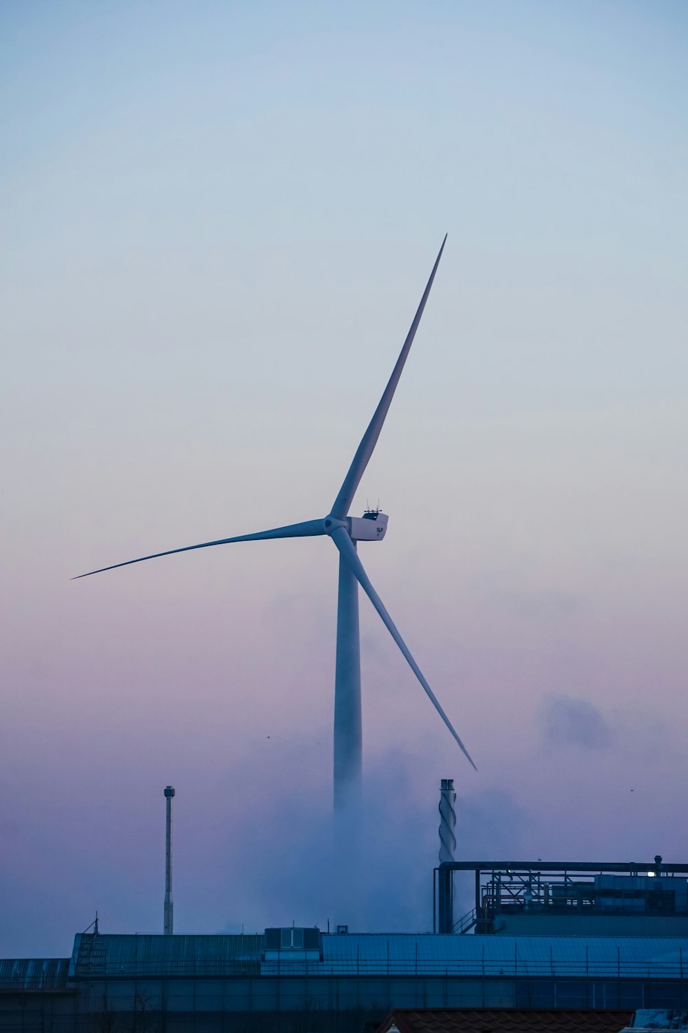 white wind turbine under gray sky