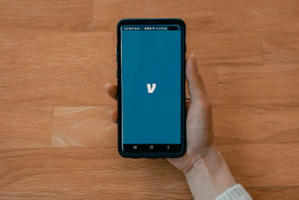 A sleek smartphone displaying the vashbook app with a vibrant blue-purple gradient interface and user-friendly profile page.
