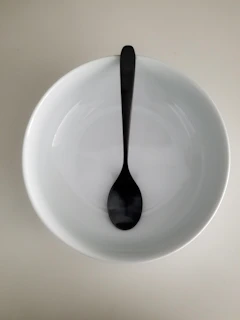An elegant spoon resting on a sleek, matte-finish bowl, ready for a comforting soup.