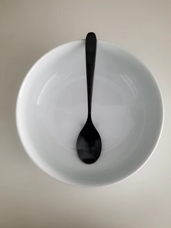 An elegant spoon resting on a sleek, matte-finish bowl, ready for a comforting soup.