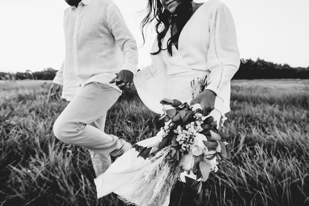 man and woman sitting on grass field in grayscale photography