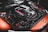 A detailed view of a car engine featuring sleek components and a cover marked with 'MPower'. The image highlights a mix of metallic textures and intricate details of the engine's design. The surrounding parts are well-organized with visible branding elements.