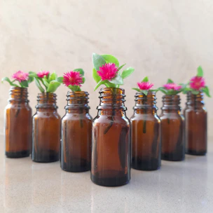Artistic arrangement of Bach flower bottles with fresh flowers and soft pastel background.