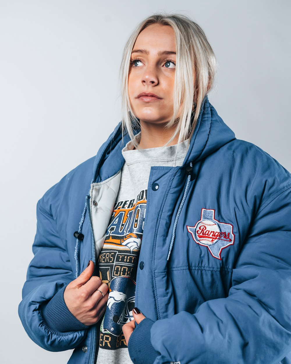 woman in blue zip up hoodie holding black and white bottle