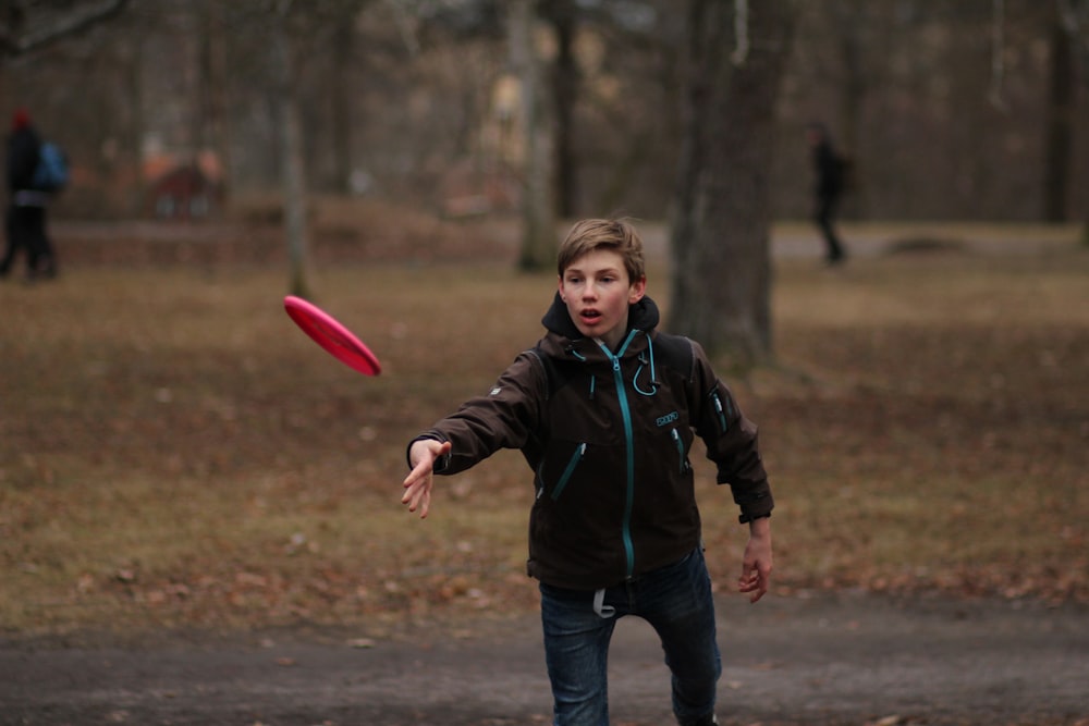 boy in green jacket holding pink balloon