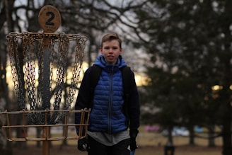 A friendly person holding a disc golf basket with a sunset in the background.