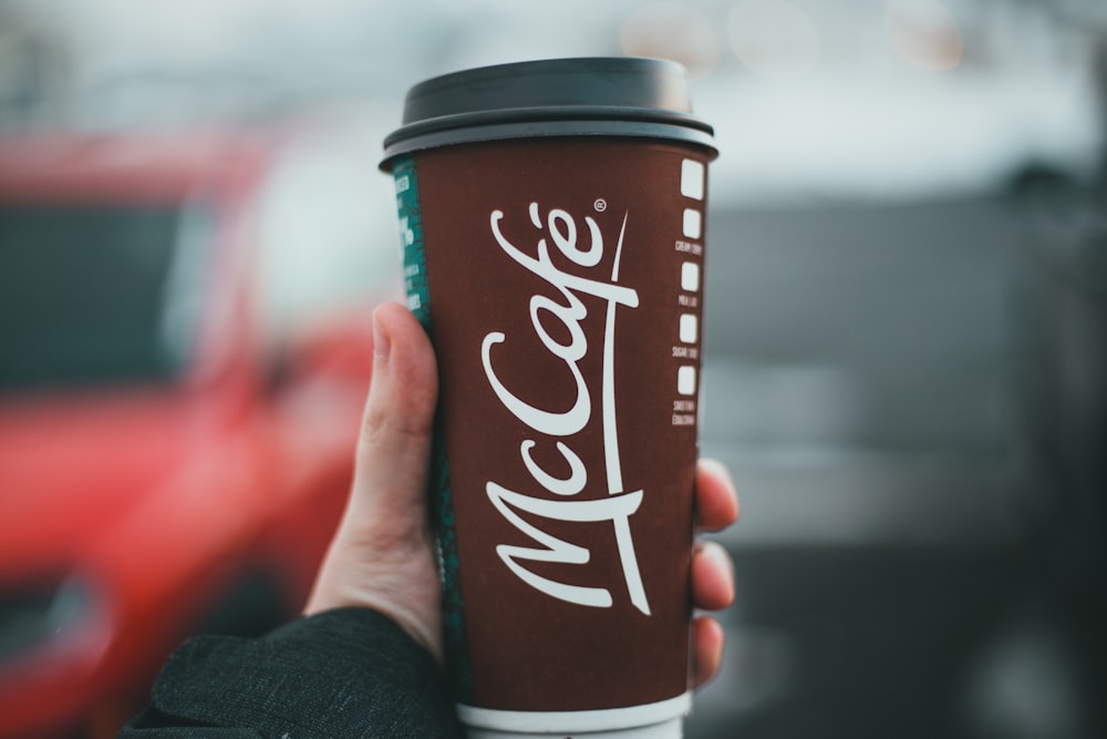 person holding a mccafe disposable cup