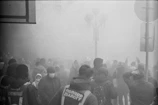 Nighttime city street scene with volunteers moving through light fog, their faces hidden but their actions clear.