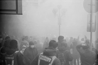 Nighttime city street scene with volunteers moving through light fog, their faces hidden but their actions clear.