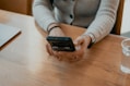 woman in white sweater holding black smartphone