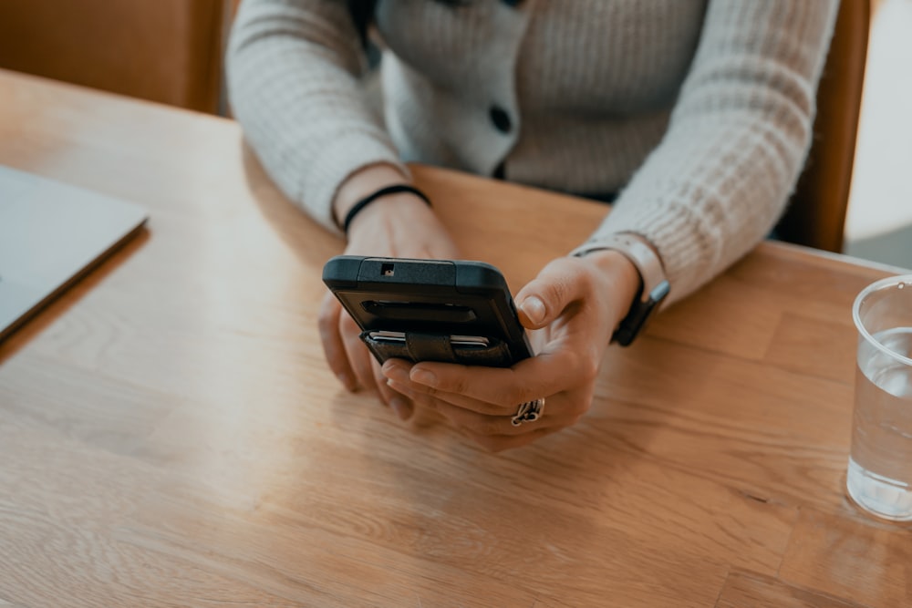 Frau im weißen Pullover mit schwarzem Smartphone