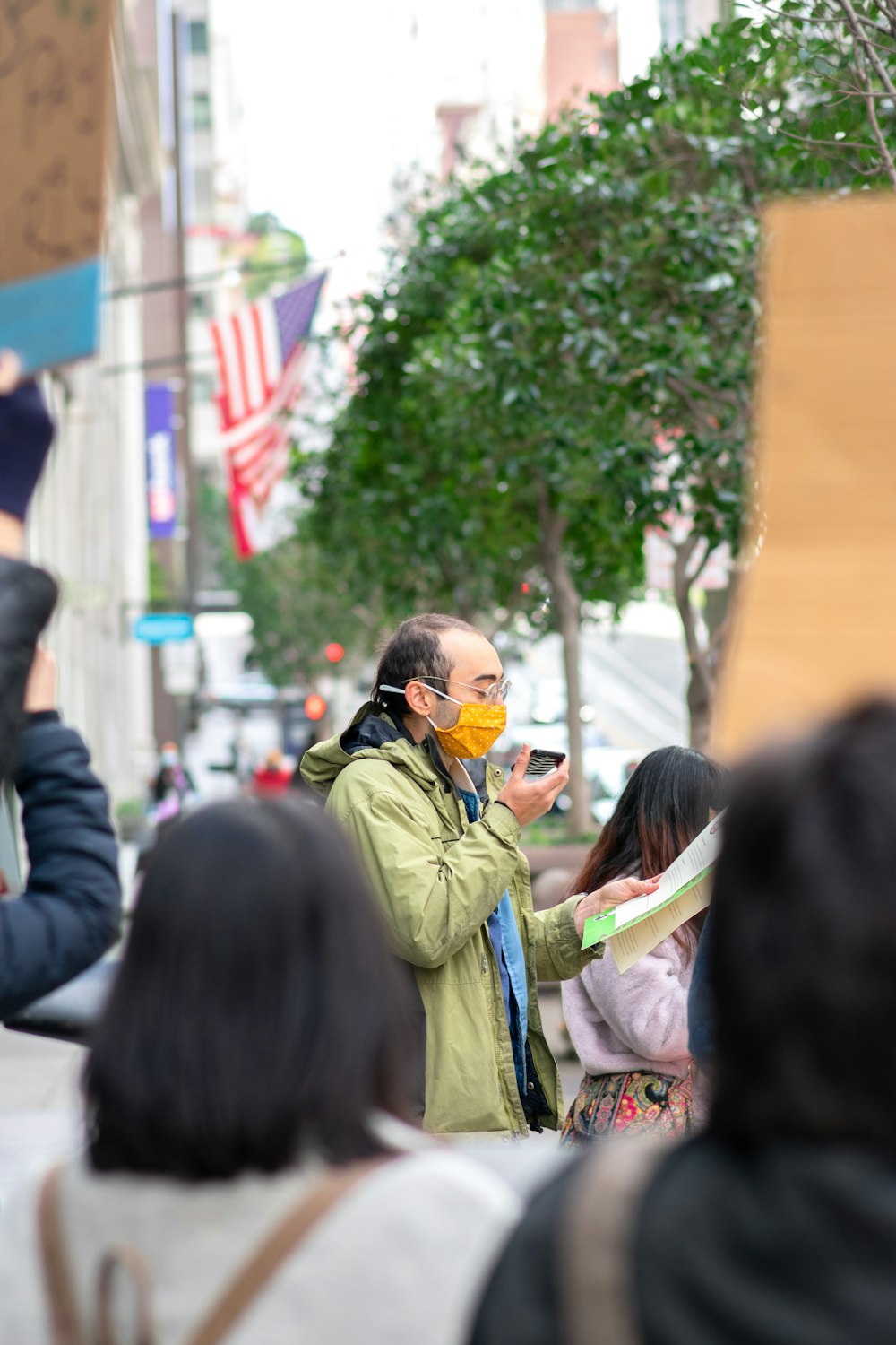 man in green jacket wearing black sunglasses holding black dslr camera