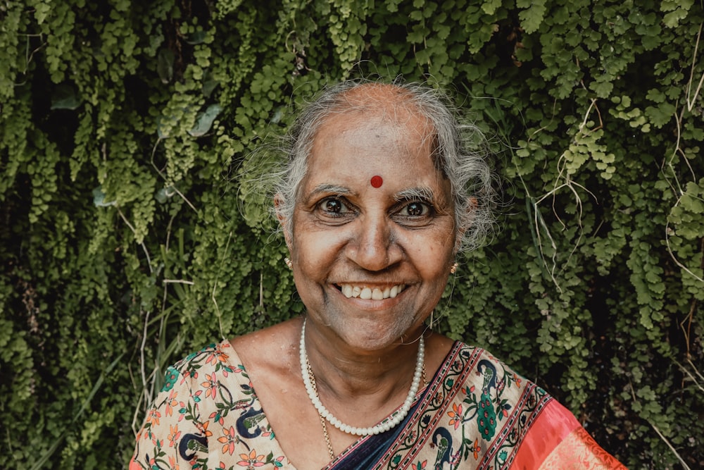 Frau im weißen, roten und grünen Blumenhemd lächelt