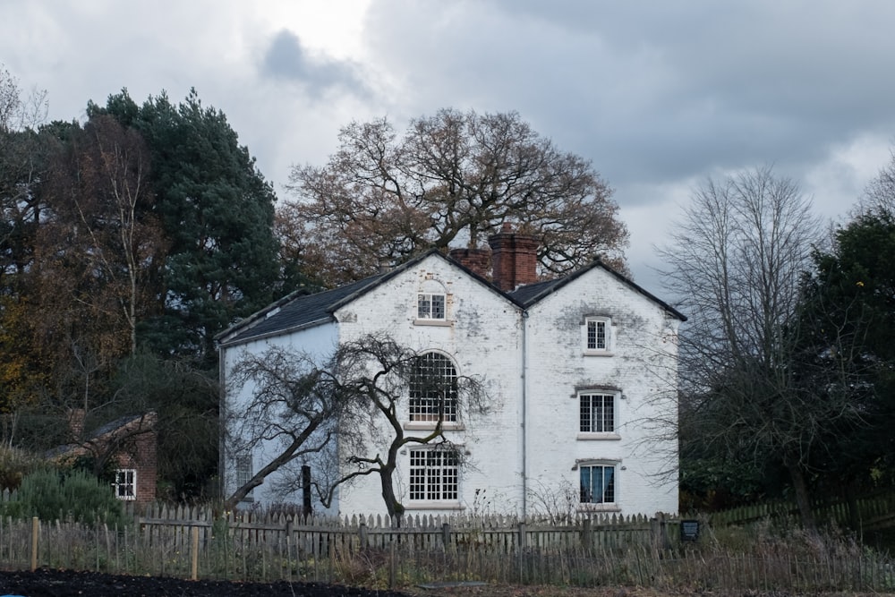 white and brown house surrounded by trees under white clouds during daytime