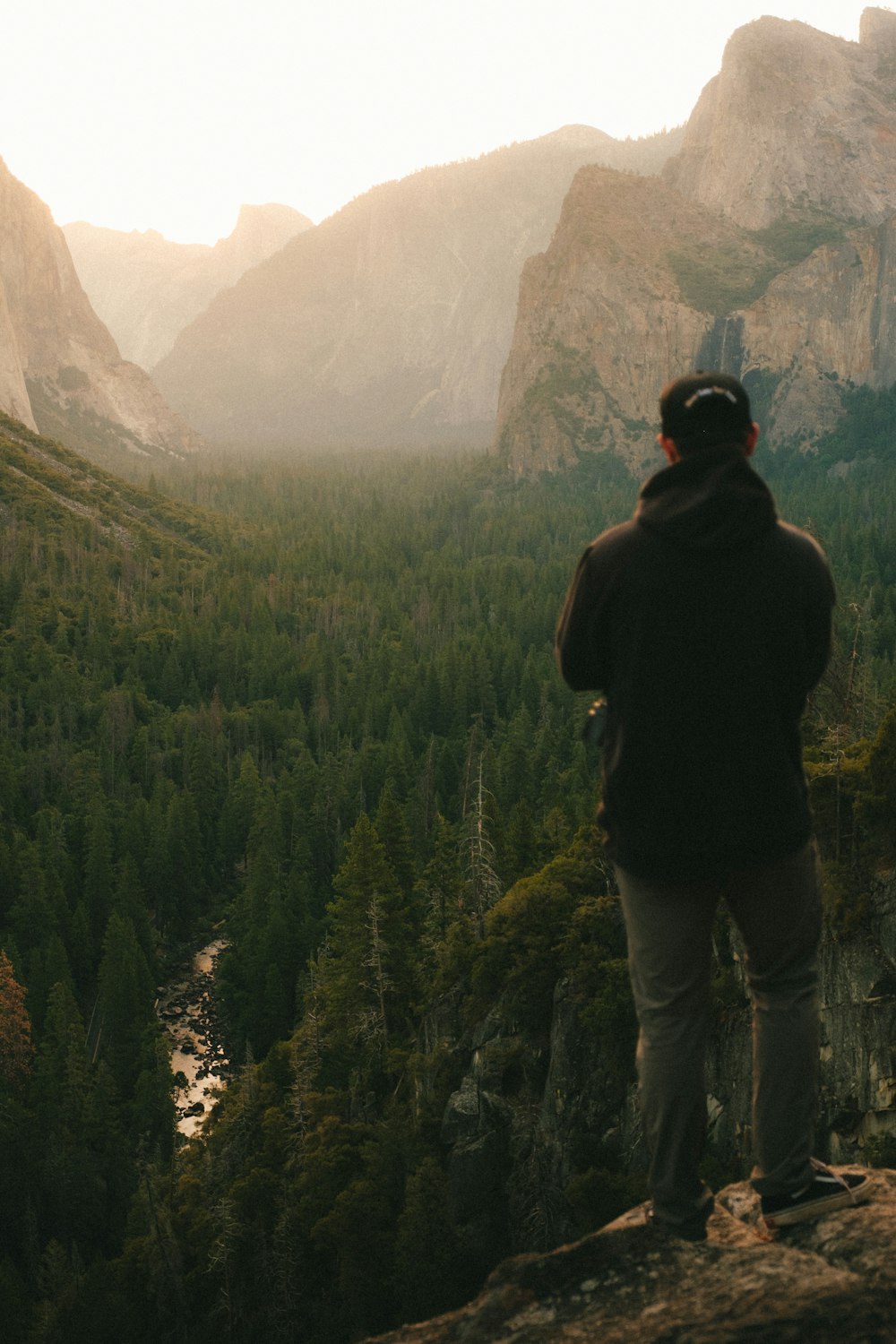 man in black jacket standing on rock formation during daytime