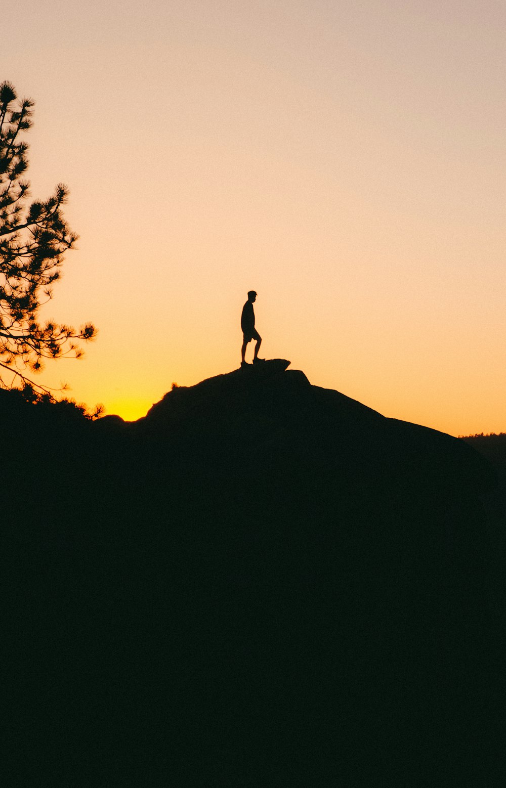 silhouette of person standing on rock formation during sunset