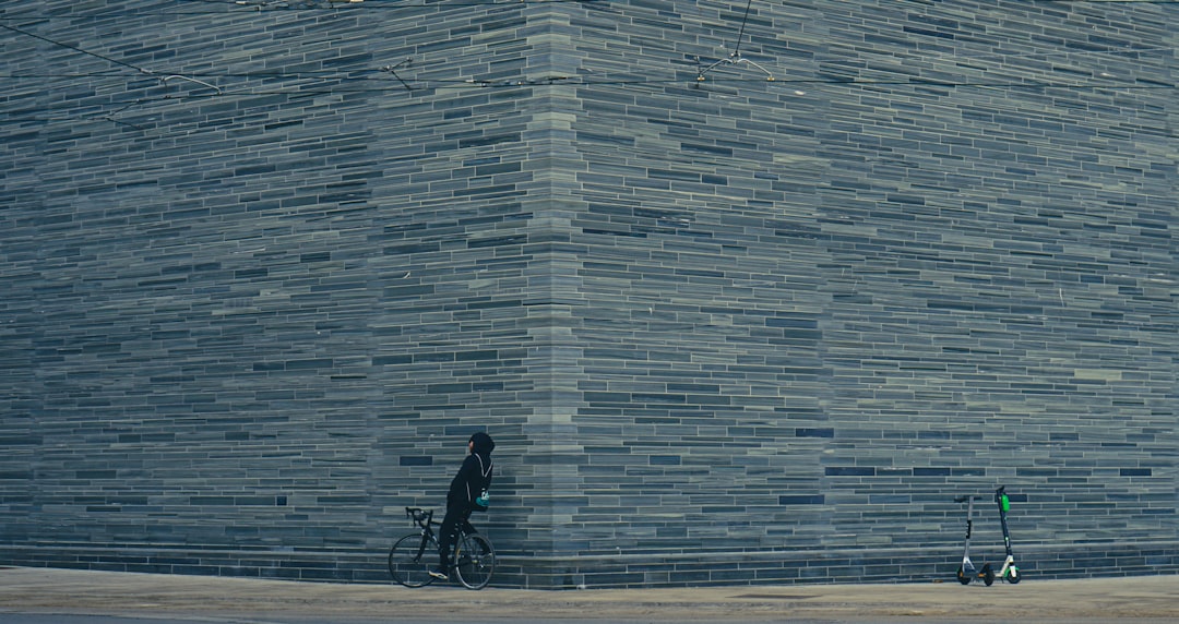 man in black jacket riding bicycle near gray concrete building during daytime