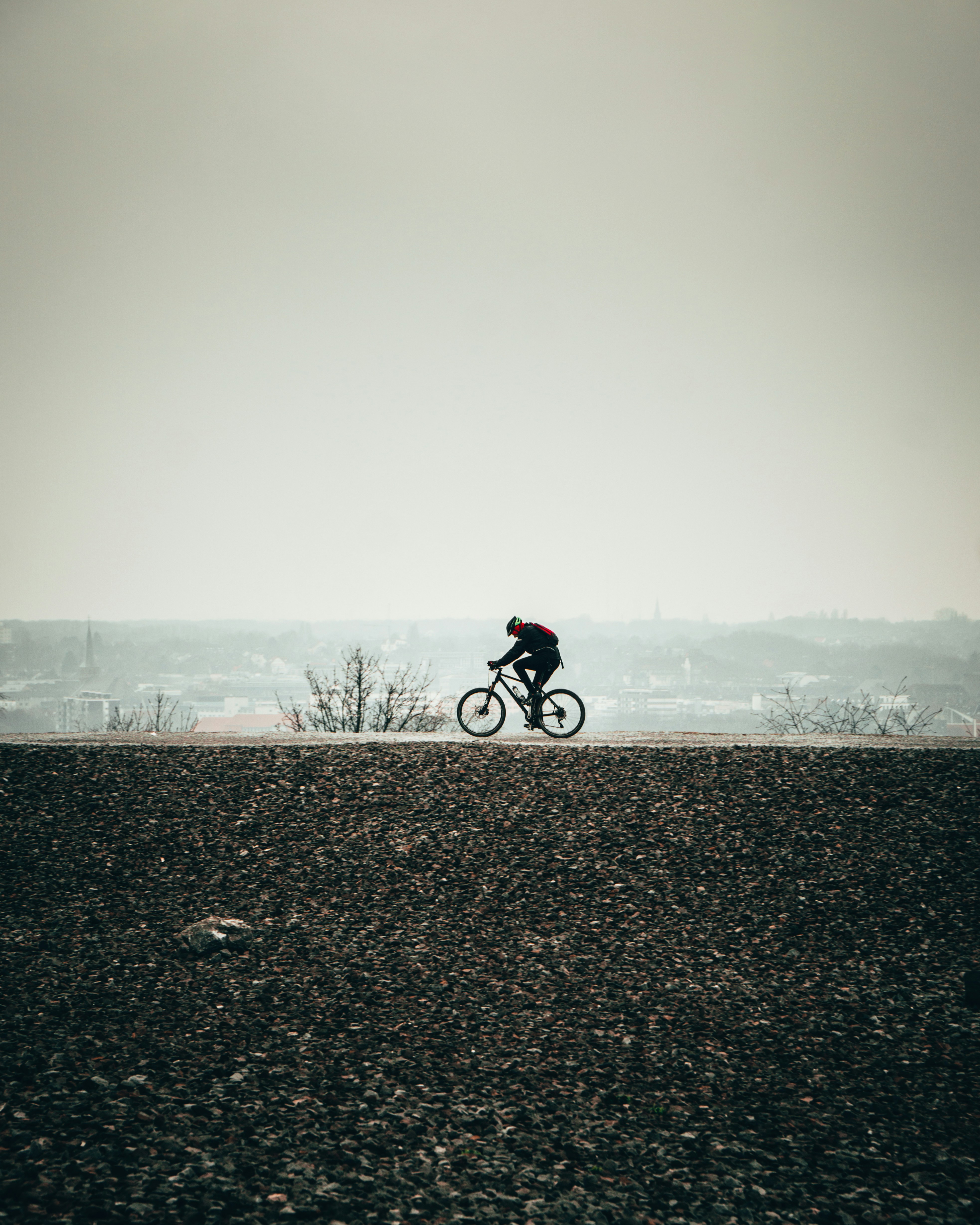 man in black jacket riding bicycle on gray sand during daytime