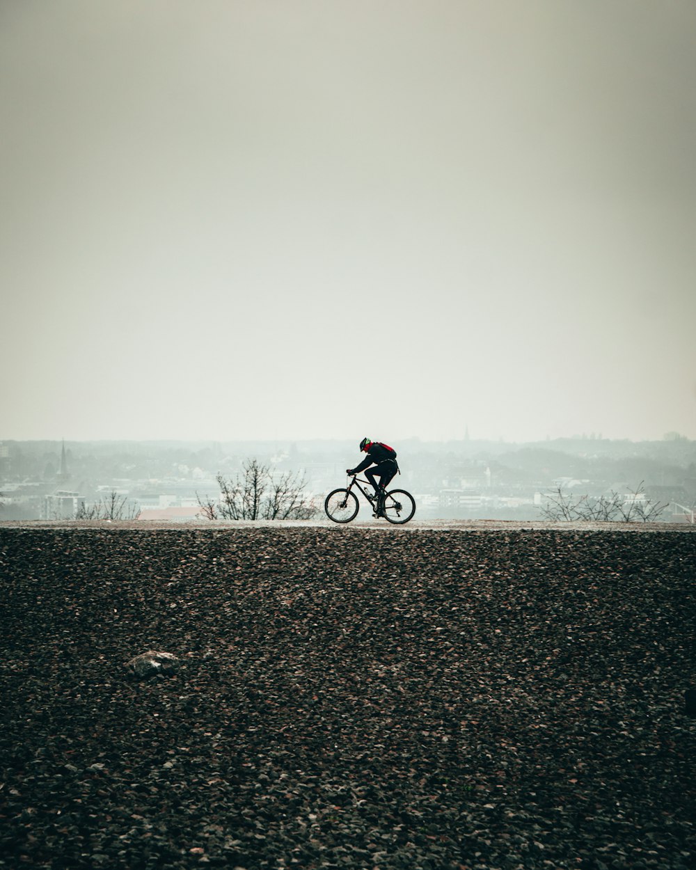 man in black jacket riding bicycle on gray sand during daytime