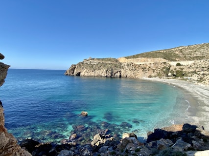 brown rocky mountain beside blue sea under blue sky during daytime