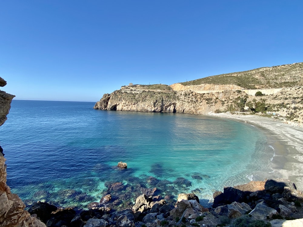 Montaña rocosa marrón junto al mar azul bajo el cielo azul durante el día