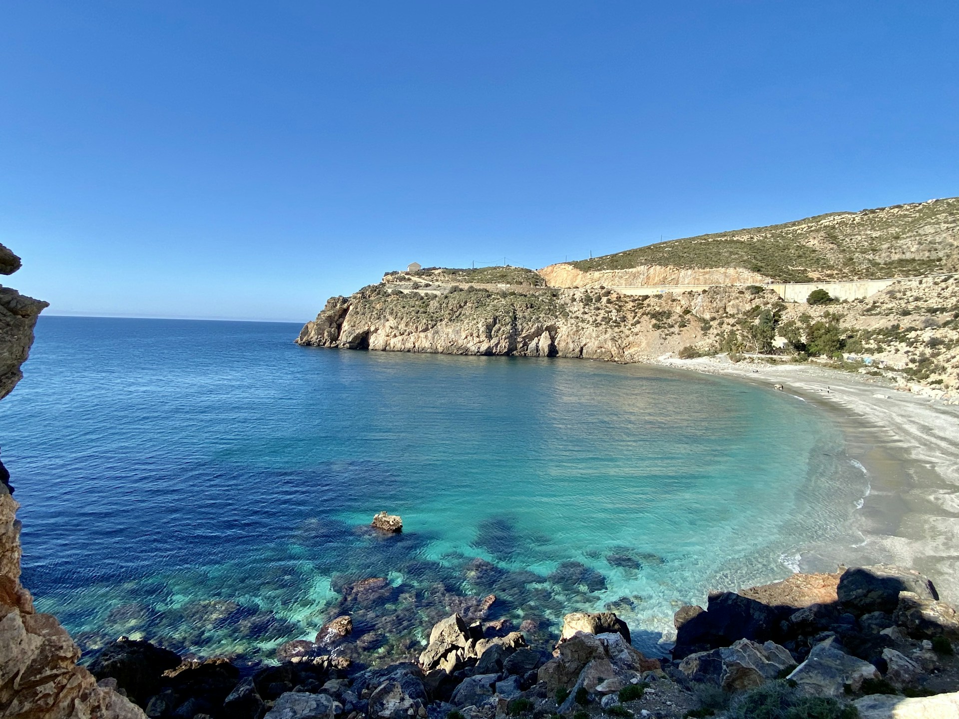 brown rocky mountain beside blue sea under blue sky during daytime