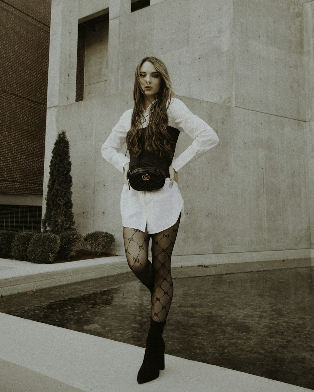 woman in white long sleeve shirt and black skirt standing beside brown brick wall