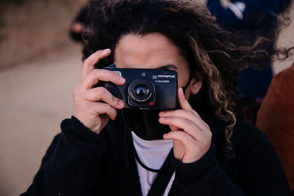 woman in black jacket holding black nikon camera