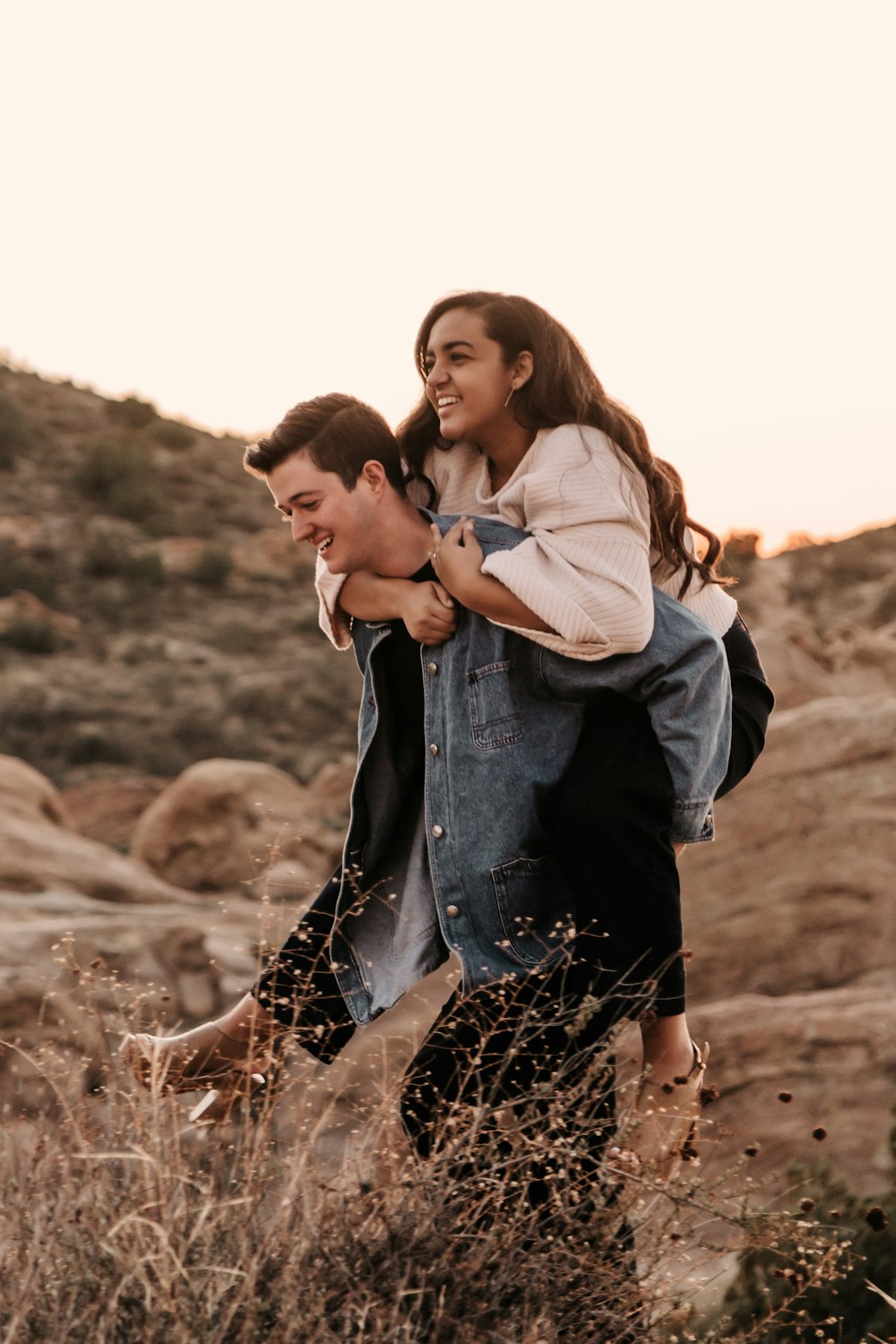 man in blue denim jacket kissing woman in white jacket during daytime