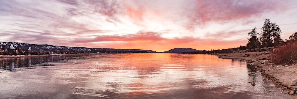 body of water near mountain during sunset