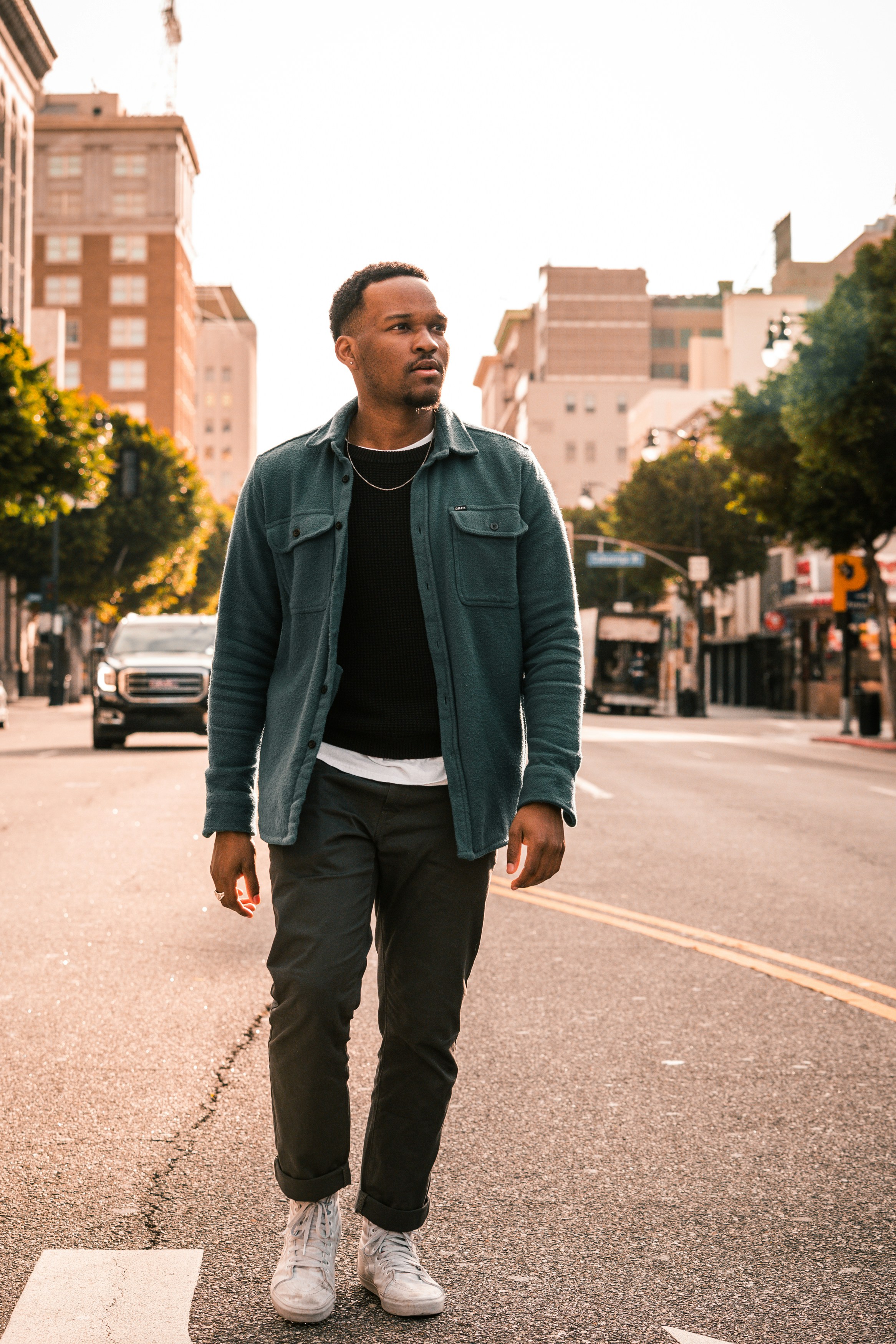 Mann in schwarzer Reißverschlussjacke steht tagsüber auf der Straße