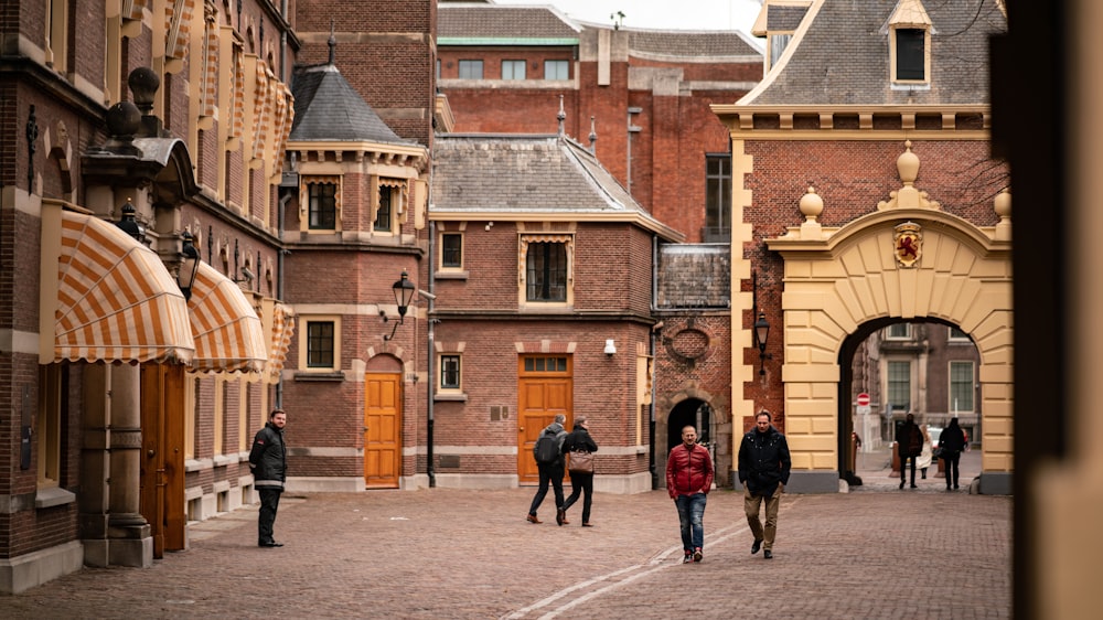 people walking on sidewalk near brown concrete building during daytime